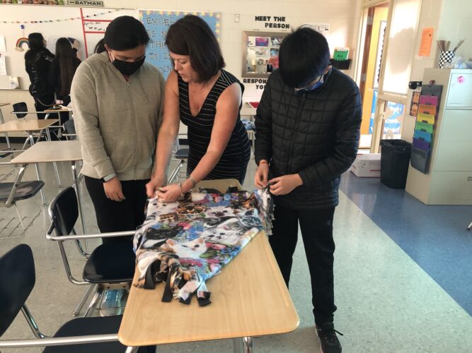 Ms. Gear works with Sergio Martinez and Makala Petersmark to create blankets for the shelter.